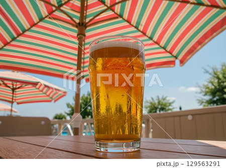 プールサイドのパラソルの下で冷えたビールを楽しむ2　AI生成画像 129563291