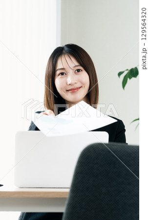 書類を手渡すビジネスウーマン 書類を手渡すビジネスウーマン 129564320
