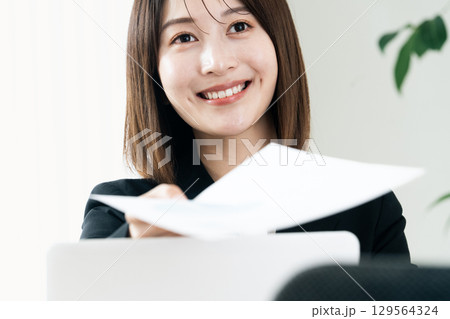 書類を手渡すビジネスウーマン 書類を手渡すビジネスウーマン 129564324