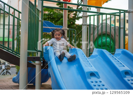 happy toddler baby girl sliding and playing at playground happy toddler baby girl sliding and playing at playground 129565109