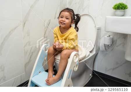 happy toddler girl is sitting on toilet at home. potty training and learning 129565110