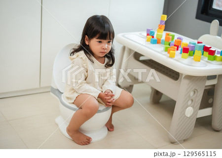 toddler girl learning sit on toilet wc seat at home. child being potty trained toddler girl learning sit on toilet wc seat at home. child being potty trained 129565115