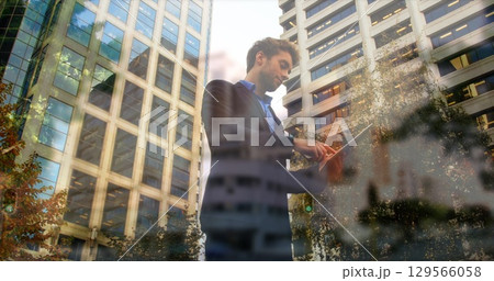 Image of timelapse with walking people over caucasian businessman using tablet 129566058