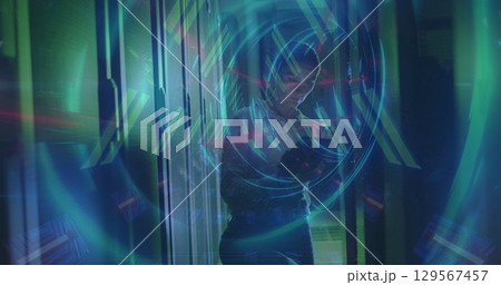 Image of tunnel made of lights over caucasian woman checking servers 129567457