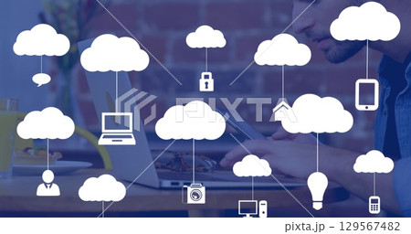 Tapping worker wearing denim shirt using tablet at cafe, with laptop, breakfast items, cloud icons 129567482