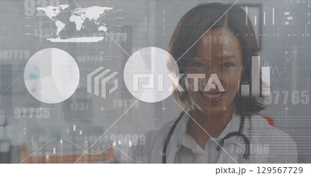 Image of interface screen with charts and data over portrait of smiling asian female doctor 129567729