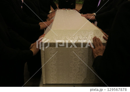 棺のふたを閉じる親族 129567878