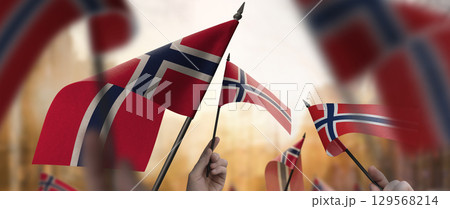 Norway flags in their hands on a blurred urban background Norway flags in their hands on a blurred urban background 129568214