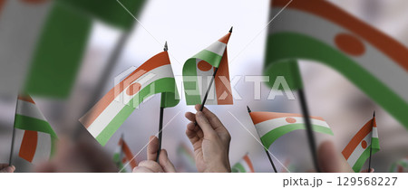 Niger flags in their hands on a blurred urban background 129568227