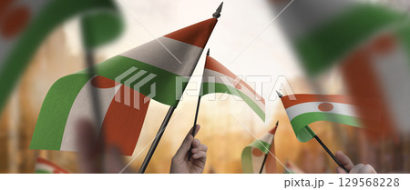 Niger flags in their hands on a blurred urban background 129568228