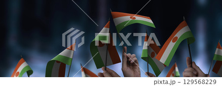 Niger flags in their hands on a blurred urban background 129568229