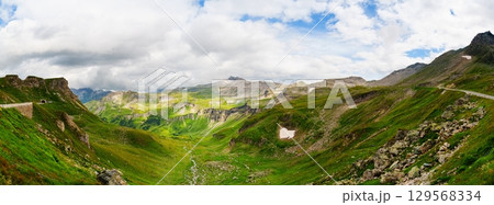 Breathtaking Mountain Pass Views Green Alpine Meadows and Dramatic Cloud Formations 129568334