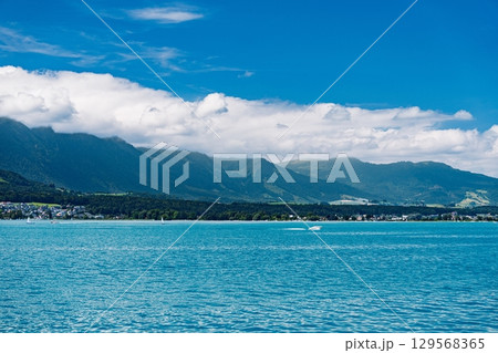 Idyllic Lake Landscape with Mountains and Clouds Under a Bright Blue Sky. Serene Scene. Idyllic Lake Landscape with Mountains and Clouds Under a Bright Blue Sky. Serene Scene. 129568365