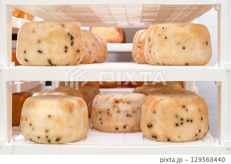 Artisanal Cheese Wheels Maturing on Shelves in a Creamery, Ready for Market, Food Concept 129568440