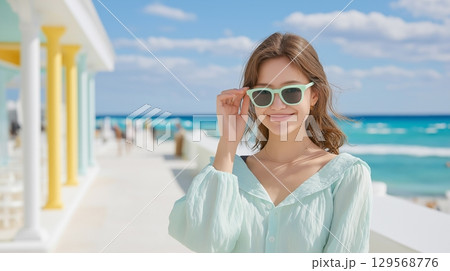 夏の海岸でサングラスをかけてポーズをとる女性 129568776