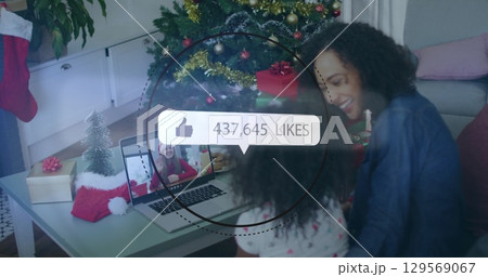 Image of media icons over mother with daughter having laptop image call 129569067
