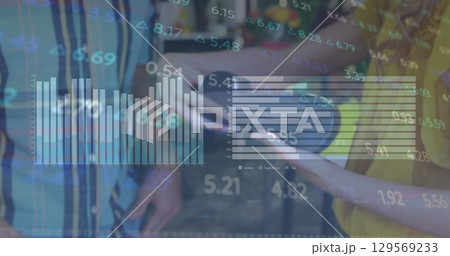 Woman in yellow and man in stripes analyzing data on outdoor terrace, with tablet, floating charts 129569233