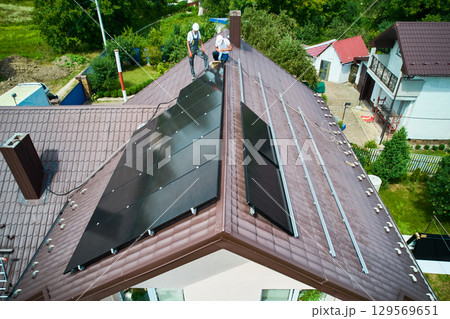 House with solar panels on rooftop for generating electricity through photovoltaic effect. Home with solar power system on roof. Concept of alternative energy, autonomy, power sustainable resources. 129569651