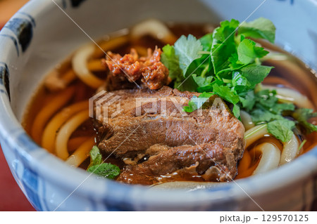 Delicious bowl of Udon Japanese noodle soup with herbs and meat Delicious bowl of Udon Japanese noodle soup with herbs and meat 129570125