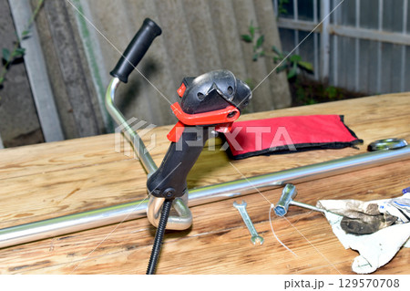 The petrol mower lies on a wooden table. The petrol mower lies on a wooden table. 129570708