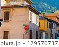 Old Italian street in Como city. Multicolor old house building architecture. Window shutter. Stop road sign and direction arrow. 129570737