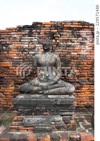 Wat Chaiwatthanaram temple, Ayutthaya historical park, Ayutthaya, Thailand Ancient Buddha statue against brick backdrop Wat Chaiwatthanaram temple, Ayutthaya historical park, Ayutthaya, Thailand Ancient Buddha statue against brick backdrop 129571480