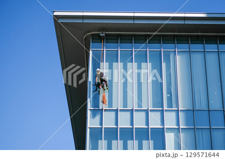 Window cleaner on high-rise building exterior Window cleaner on high-rise building exterior 129571644
