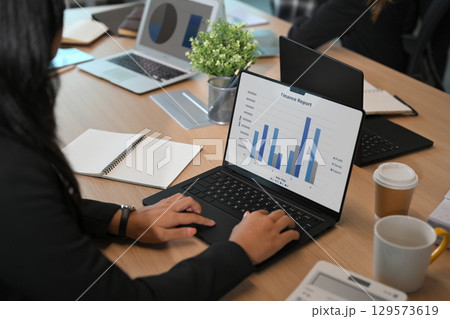 Businesswoman analyzing finance report on laptop during a corporate meeting in modern office 129573619