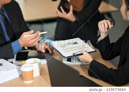 Businesspeople working on financial documents and analytics during meeting Businesspeople working on financial documents and analytics during meeting 129573664