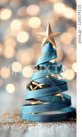 Christmas tree made of blue ribbon spirals adorned with a golden star, glowing lights in the background creating a festive atmosphere 129574115