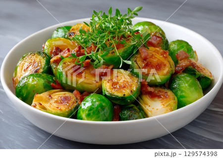 Roasted brussels sprouts with crispy bacon and fresh thyme in a bowl 129574398