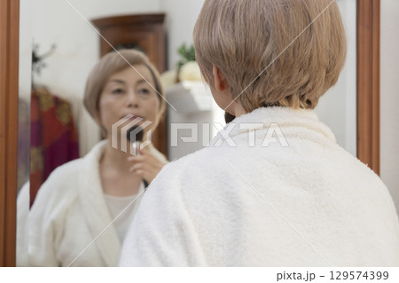 鏡の前で化粧をするシニア女性 129574399