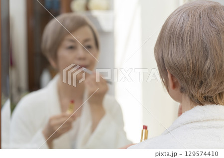 鏡の前で化粧をするシニア女性 鏡の前で化粧をするシニア女性 129574410