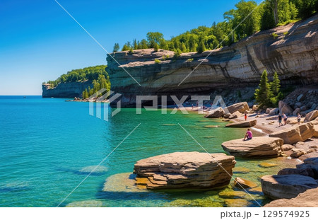 Peaceful view of rocky shoreline with golden cliffs and blue water under soft sky in scenic remote lakeside landscape 129574925