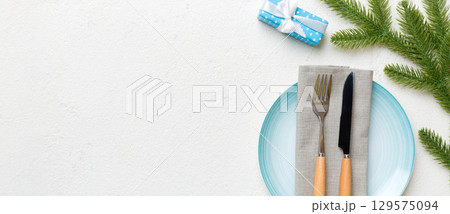 Christmas table place setting with christmas decor and plates, kine, fork and spoon. Christmas holiday background. Top view with copy space 129575094