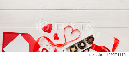 Envelope on colored background for Valentine Day with gift box and chocolate. Heart shaped with gift box of chocolates top view with copy space Envelope on colored background for Valentine Day with gift box and chocolate. Heart shaped with gift box of chocolates top view with copy space 129575113