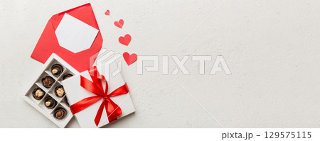 Envelope on colored background for Valentine Day with gift box and chocolate. Heart shaped with gift box of chocolates top view with copy space Envelope on colored background for Valentine Day with gift box and chocolate. Heart shaped with gift box of chocolates top view with copy space 129575115