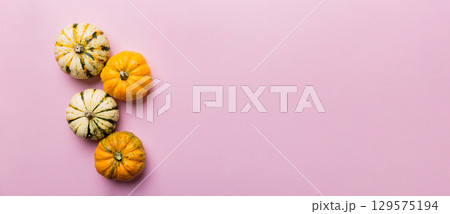 Autumn composition of little orange pumpkins on colored table background. Fall, Halloween and Thanksgiving concept. Autumn flat lay photography. Top view vith copy space Autumn composition of little orange pumpkins on colored table background. Fall, Halloween and Thanksgiving concept. Autumn flat lay photography. Top view vith copy space 129575194