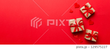 Valentine day composition: red gift box with bow and heart. Christmas present. View from above. Space for text. Holday greeting card 129575227