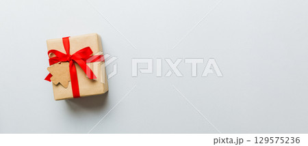 wrapped christmas or other holiday handmade present in paper with colored ribbon. Present box, decoration of gift on colourfull table, top view with copy space wrapped christmas or other holiday handmade present in paper with colored ribbon. Present box, decoration of gift on colourfull table, top view with copy space 129575236