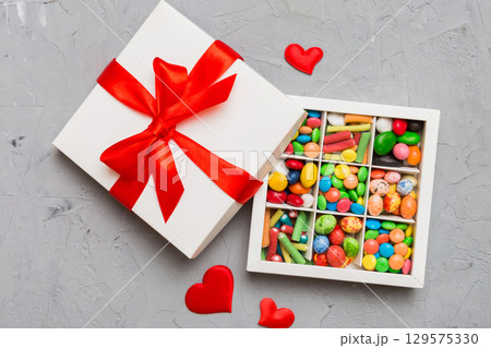 Valentine day composition: sweet candy, with gift boxes with bow and red felt hearts, photo template, background. Top View with copy space Valentine day composition: sweet candy, with gift boxes with bow and red felt hearts, photo template, background. Top View with copy space 129575330