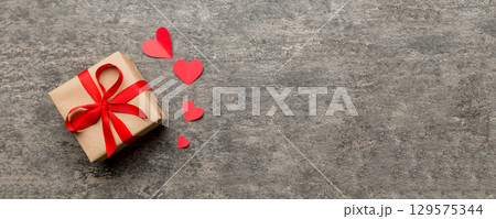Valentine day composition: red gift box with bow and heart. Christmas present. View from above. Space for text. Holday greeting card 129575344