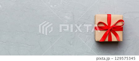 Valentine day composition: red gift box with bow and heart. Christmas present. View from above. Space for text. Holday greeting card Valentine day composition: red gift box with bow and heart. Christmas present. View from above. Space for text. Holday greeting card 129575345