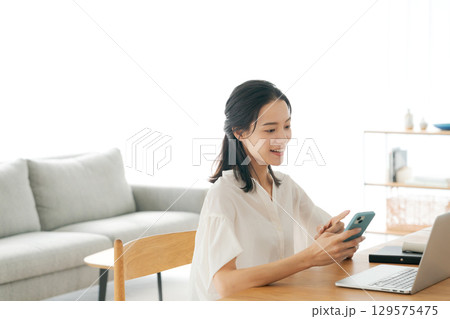 リビングでスマホを持つ女性 リビングでスマホを持つ女性 129575475