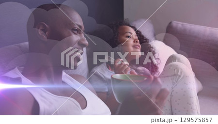 Image of clouds and light trails over african american man and his daughter eating together 129575857