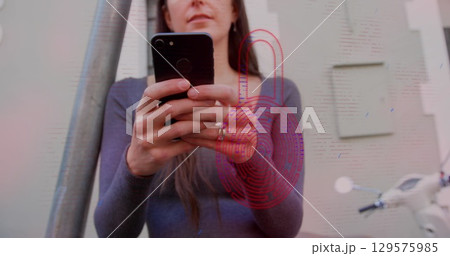 Image of security padlock icon over caucasian woman using smartphone outdoors Image of security padlock icon over caucasian woman using smartphone outdoors 129575985