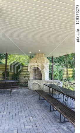 A tall brick oven in a gazebo in nature for cooking food on fire and skewers. A tall brick oven in a gazebo in nature for cooking food on fire and skewers. 129576278