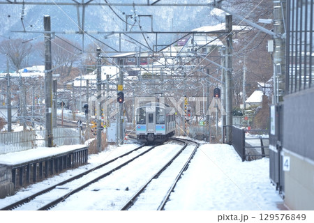 正月2日、雪が残るJR篠ノ井線姨捨(おばすて)駅、普通上り列車E127系がスイッチバックの斜面に挑む 129576849