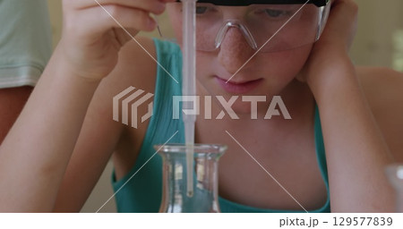 Image of glowing lights over caucasian girl with pipette and chemistry beaker Image of glowing lights over caucasian girl with pipette and chemistry beaker 129577839