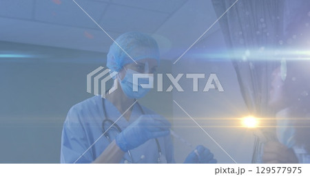 Image of light spot and light trails over female health workers working at hospital Image of light spot and light trails over female health workers working at hospital 129577975